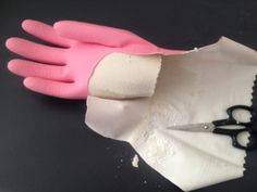 a pair of pink and white gloves sitting on top of a piece of paper next to scissors