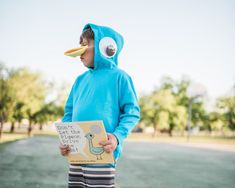 a boy in a blue bird costume holding a book