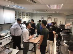 a group of people standing in a kitchen next to a table with food on it