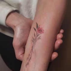 a woman holding her arm with a flower tattoo on it's left forearm and wrist