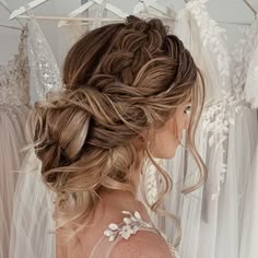 the back of a bride's head with her wedding dress hanging in the background