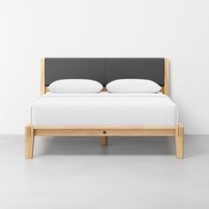 a bed with two pillows on top of it and a headboard made out of wood