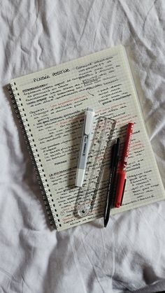 an open notebook and pen on top of a bed