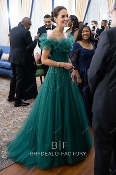 a woman in a green ball gown standing next to another man wearing a suit and tie