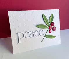 a card with the word peace written on it and two cherries attached to it