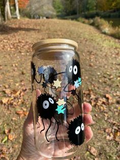 a person holding up a glass with stickers on it in front of some leaves