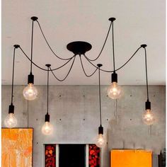 a chandelier with five light bulbs hanging from it's ceiling and two paintings on the wall