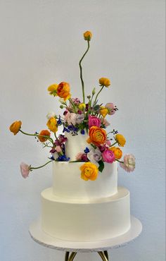 Fresh flowers on a three tier wedding cake. Cake With Ranunculus, Two Tiered Floral Cake, Bright Flower Cake, Wedding Cake Designs One Tier, Artsy Wedding Cake, Funky Wedding Cake, Dessert Table Wedding Ideas, Small Flower Cake, Cake With Bright Flowers