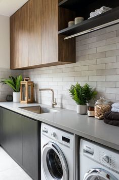 a washer and dryer sitting in a kitchen next to a counter with plants on it