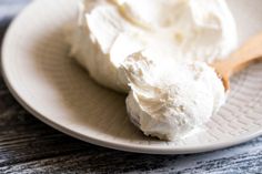 a white plate topped with whipped cream next to a wooden spoon