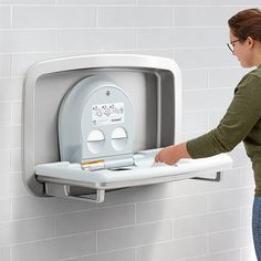 a woman is holding onto the wall mounted toilet paper dispenser