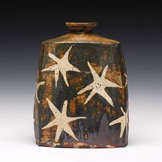 a brown and black vase with white stars on it