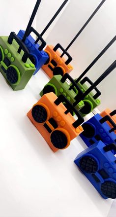 four different colored toy cars sitting next to each other on a white surface with black handles