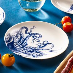 a blue and white plate with an octopus on it next to tomatoes, peppers, and other food items