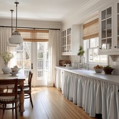 a kitchen with wooden floors and white cabinets, along with a dining room table set for four