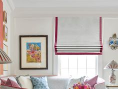 a living room filled with lots of furniture next to a window covered in roman shades