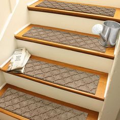 a set of stairs with carpet mats on the bottom, and a cup sitting on top