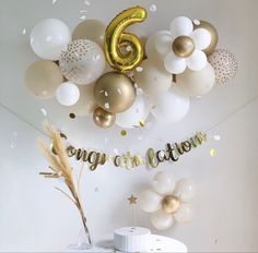 balloons and confetti are hanging from the ceiling above a table with a cake