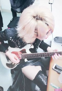 a woman with blonde hair playing an electric guitar