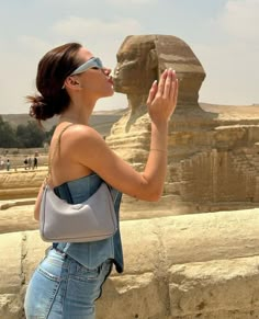 a woman standing in front of the sphinx at giza with her hand up to her mouth