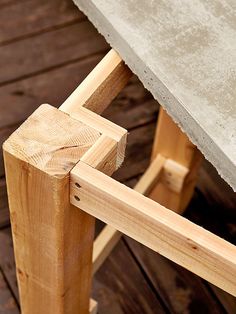 a wooden bench sitting on top of a wooden floor next to a cement tablecloth