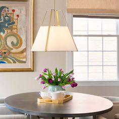 a dining room table with chairs and a vase filled with flowers on top of it