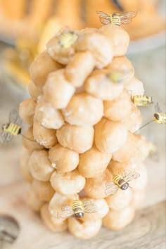 a bunch of donuts that are sitting on a wooden table with bees flying around them