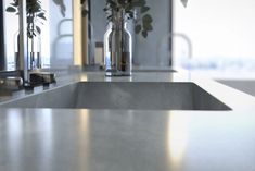 a kitchen counter with two vases filled with flowers on top of it and mirrors in the background