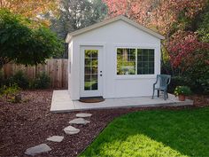 a small white shed sitting in the middle of a yard