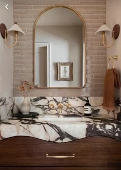 a bathroom vanity with marble counter top and gold accents