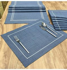 placemats and napkins are laid out on a wooden table with silverware