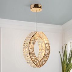 a light fixture hanging from the ceiling in a room with a potted plant next to it