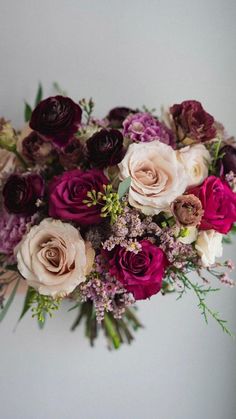 a bunch of flowers that are sitting on a table in front of a white wall