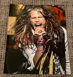 a man with long hair holding a microphone in his right hand and singing into the microphone