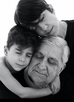 an older man hugging a young boy with his face close to him and the child's head resting on his shoulders