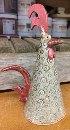 a ceramic rooster sitting on top of a wooden table