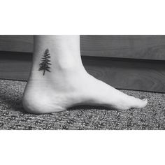 a small pine tree tattoo on the right side of the foot, which is black and white