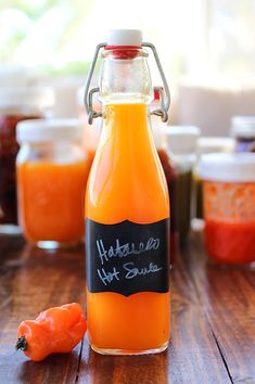 an orange juice in a glass bottle with a chalkboard label on it and two peppers next to it