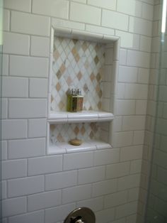 a white tiled shower with shelves above it