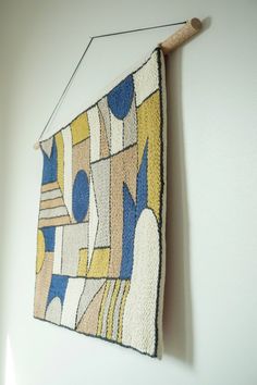 a wall hanging on the side of a white wall with a colorful rug attached to it