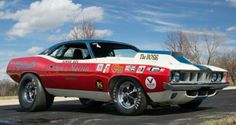 a red and white muscle car with stickers on it's hood parked in a parking lot