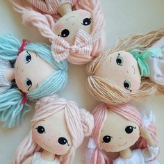 four little dolls sitting next to each other on top of a white table with pink and blue hair