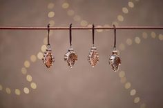 three pairs of earrings hanging from a line with boke lights in the back ground