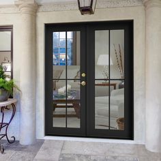 a black double door with glass panels on the front of a house next to a table and potted plant