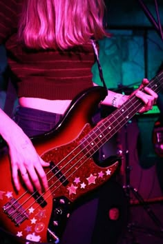 a woman playing a bass guitar in front of a microphone