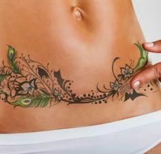 a woman's stomach with tattoos on it and her hand touching the side of her stomach