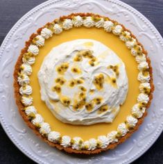 a white plate topped with a pie covered in whipped cream and yellow flowers on top