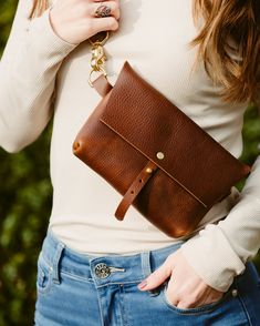 a woman is holding a brown leather purse