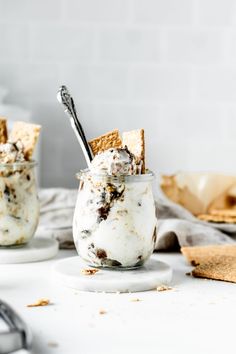 two jars filled with ice cream and crackers on top of a white countertop