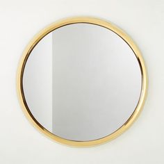 a round mirror on the wall with a gold ring around it's edge,